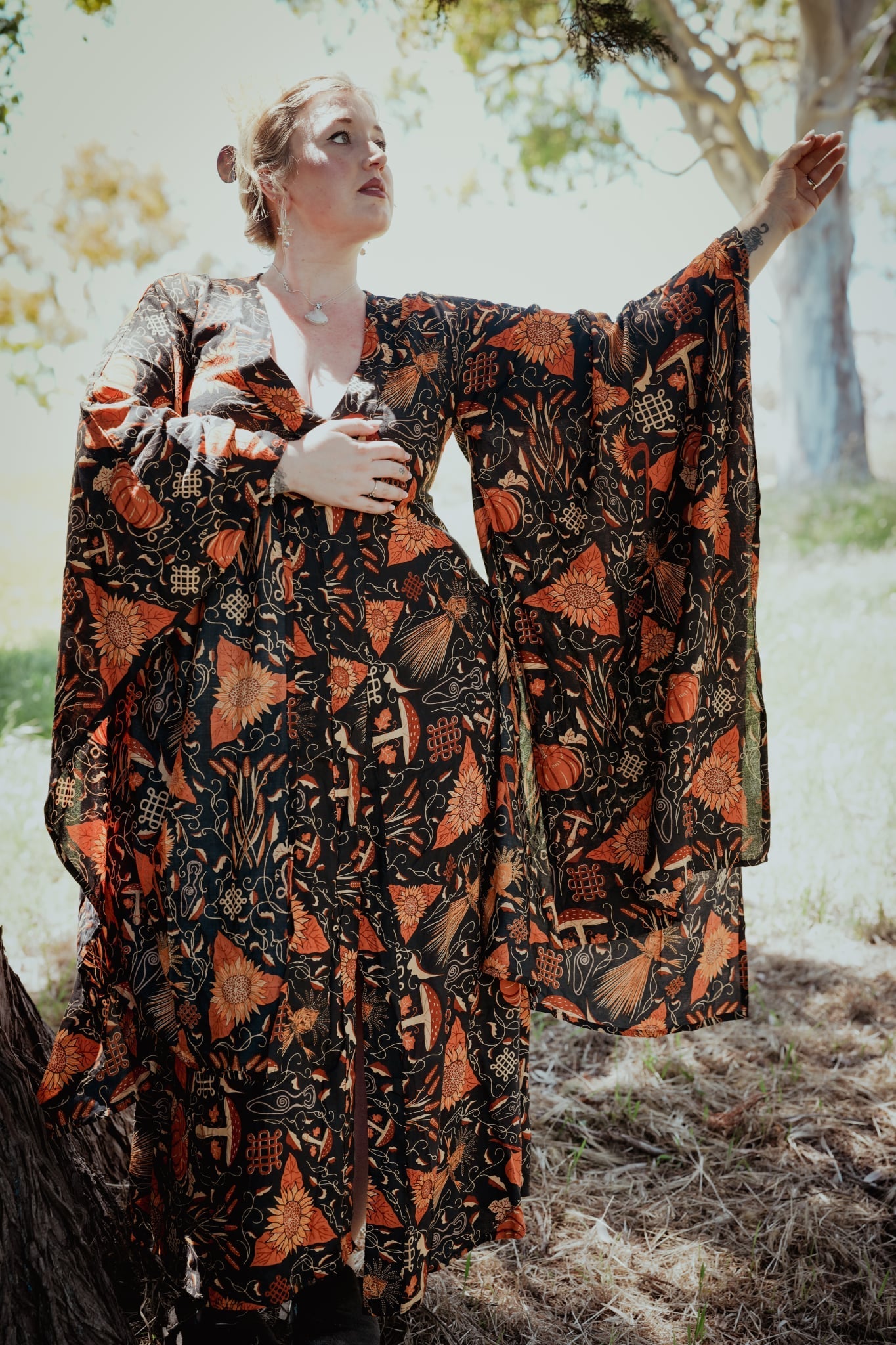 Woman wearing a patterned dress standing outdoors with trees in the background