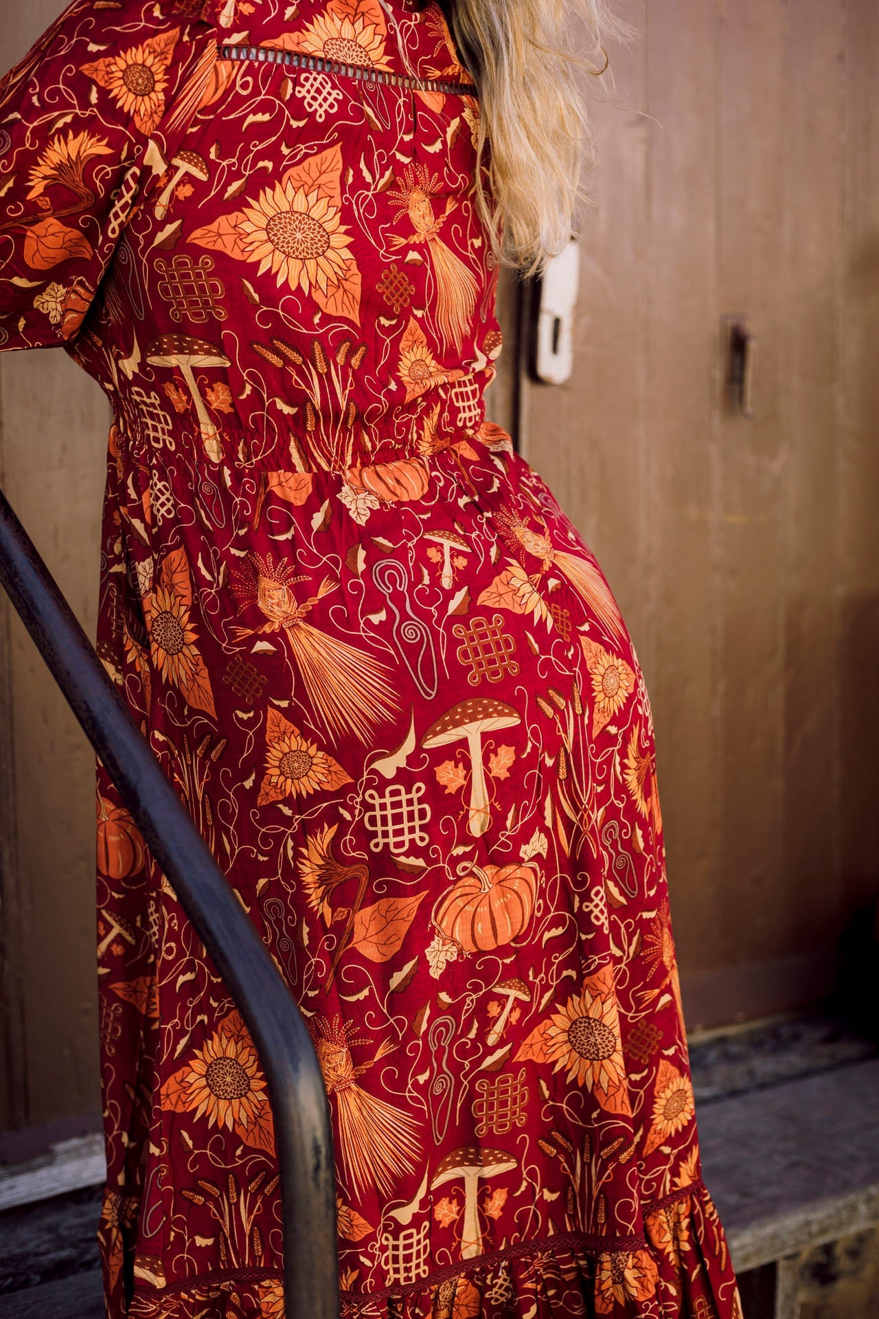 Red dress with intricate gold patterns worn by a person, against a neutral background.