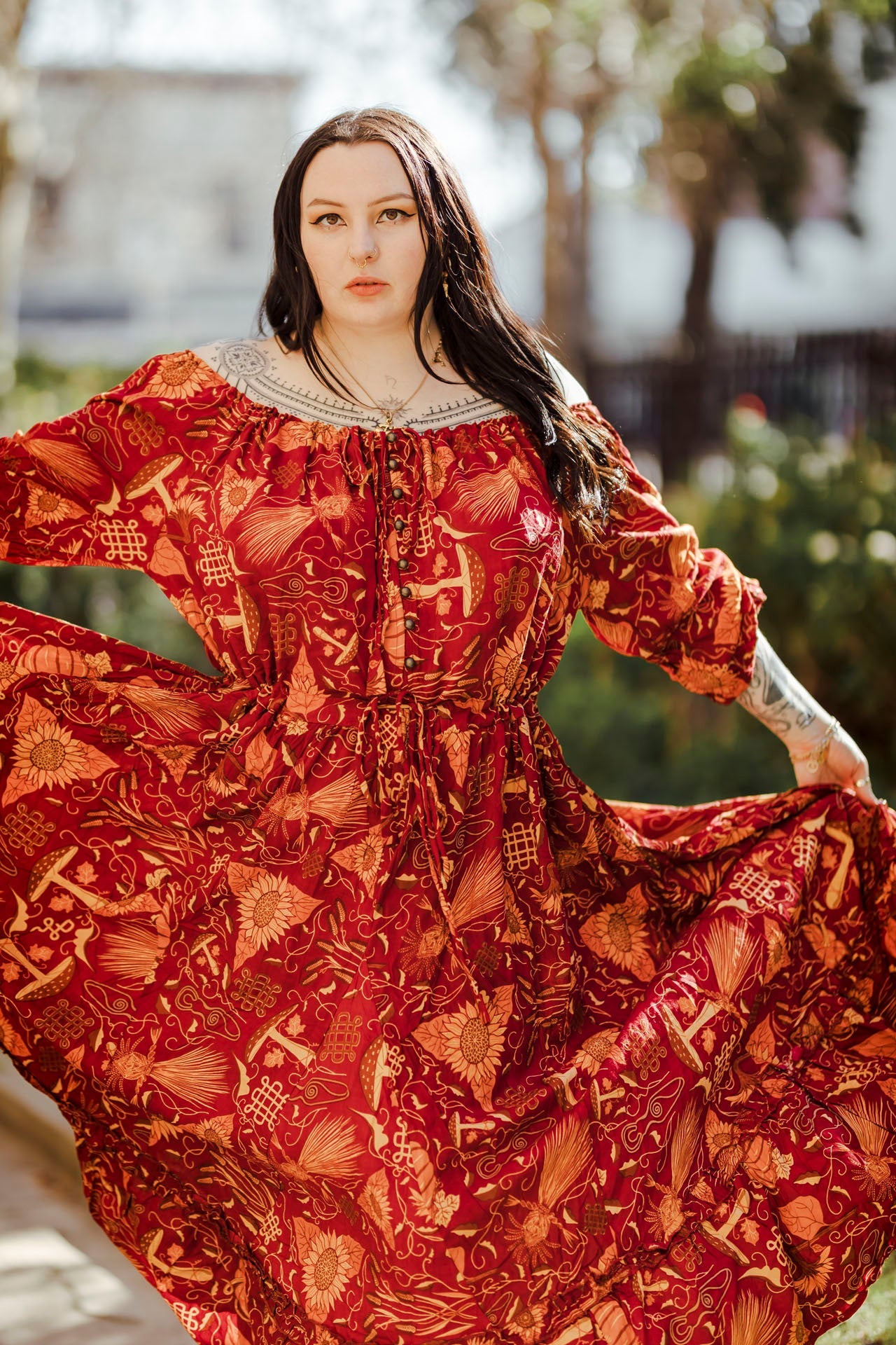 Woman wearing a red patterned dress with a blurred outdoor background