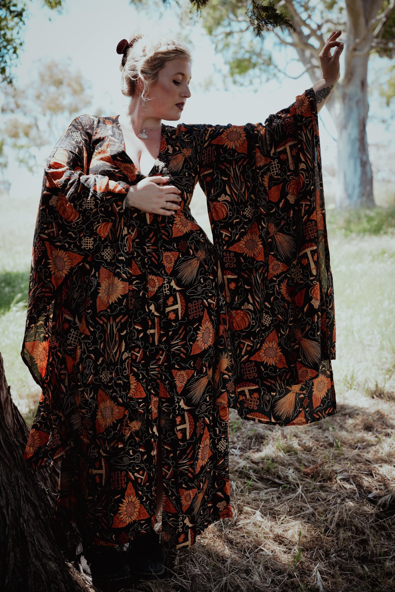 Woman in a patterned dress standing outdoors with trees in the background